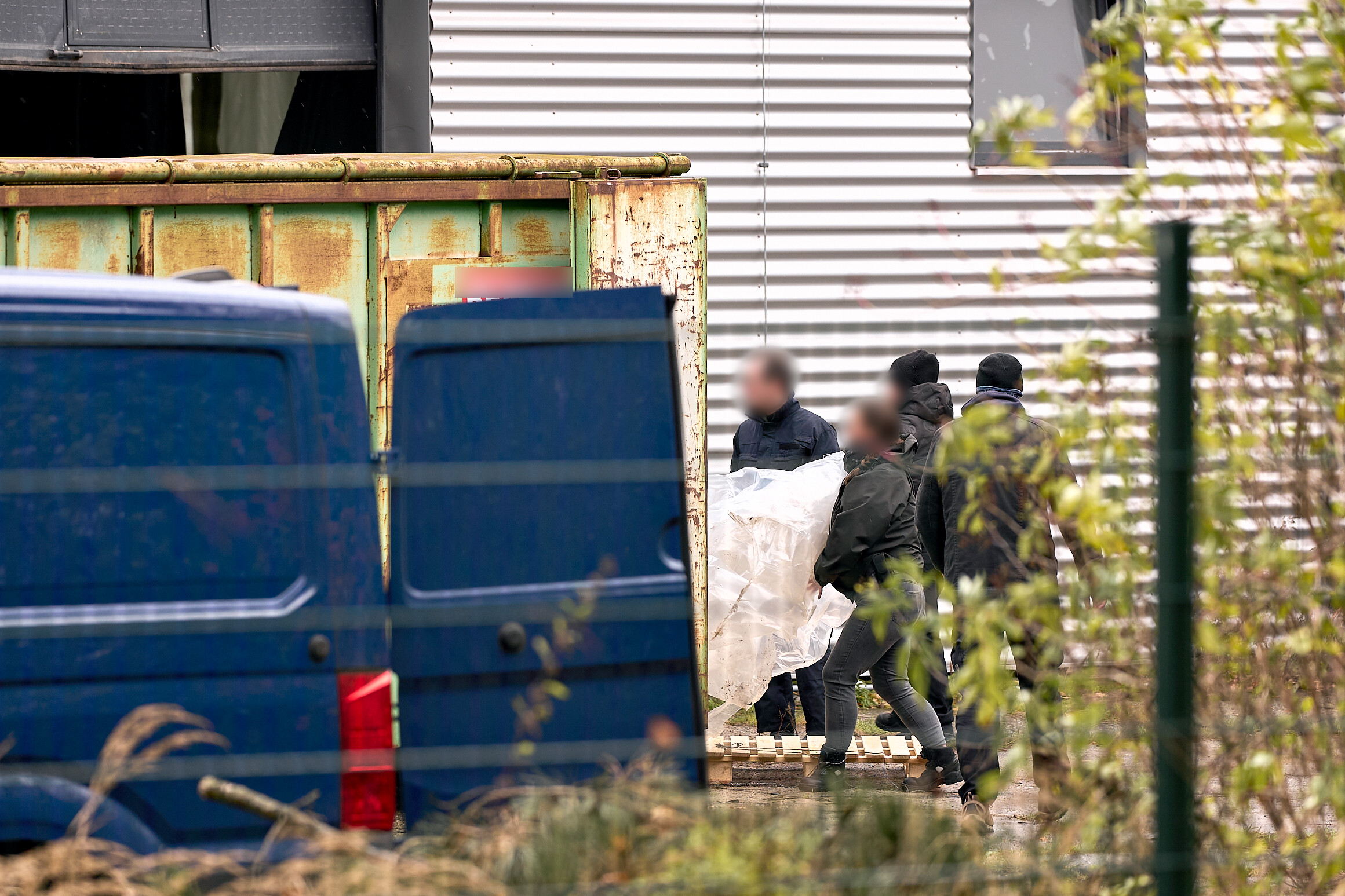 Zollbeamte tragen Utensilien aus einer Halle, in der ein riesiges illegales Drogenlabor ausgehoben wurde.