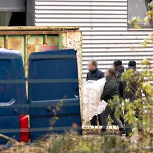 Zollbeamte tragen Utensilien aus einer Halle, in der ein riesiges illegales Drogenlabor ausgehoben wurde.