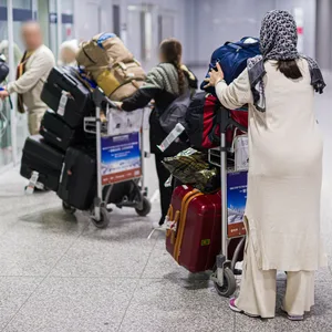 Menschen aus Afghanistan verlassen mit ihrem Gepäck das Flughafengebäude.