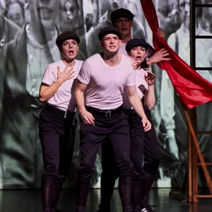 Vier Schauspieler stehen mit einer roten Flagge auf der Bühne.