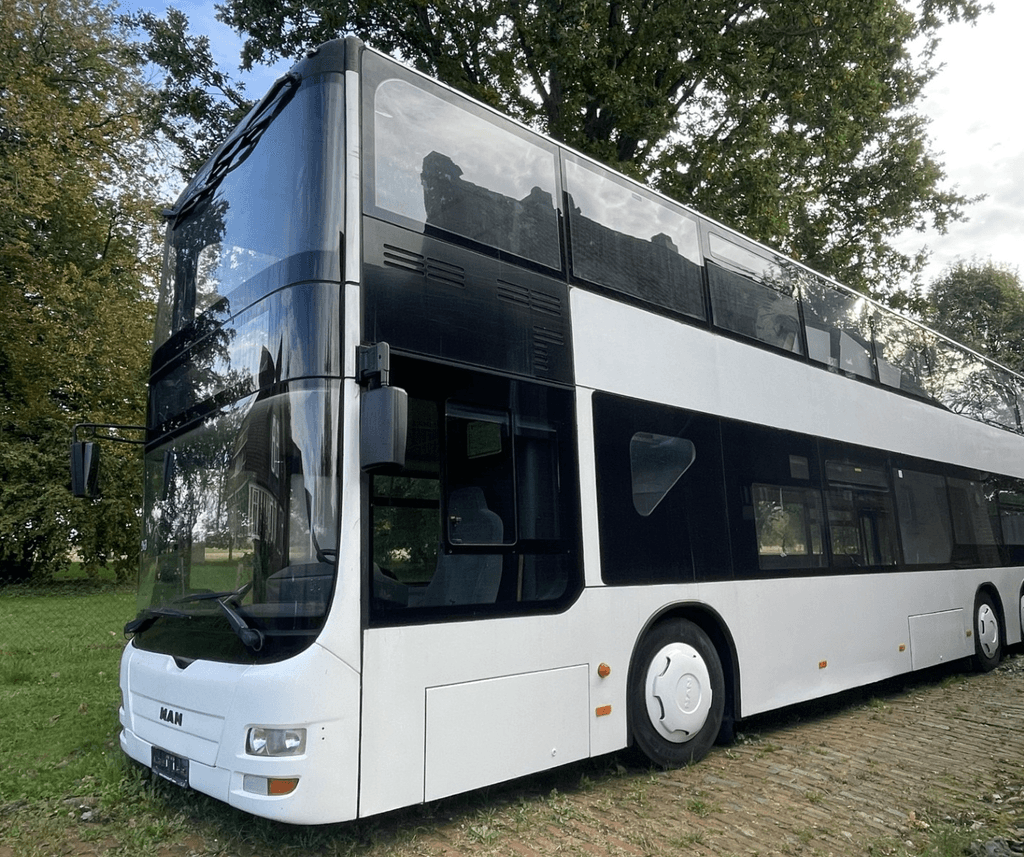 Das Bild zeigt den weißen Doppeldeckerbus auf einer Wiese stehend.