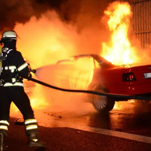 Feuerwehrleute löschen den brennenden Audi.