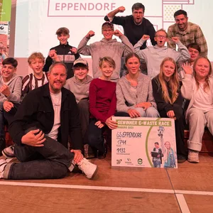 Die Schüler und Lehrer der Klasse 7e sitzen auf der Bühne der Aula und jubeln mit ausgestreckten Armen. Ganz vorne sitzt Oke Göttlich, der zur Feier des Tages persönlich vorbeigekommen ist.