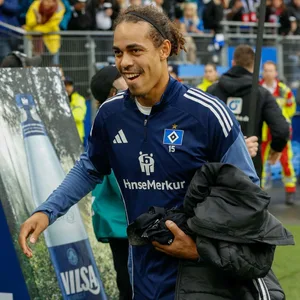 Yussuf Poulsen lächelt vor der HSV-Auswechselbank