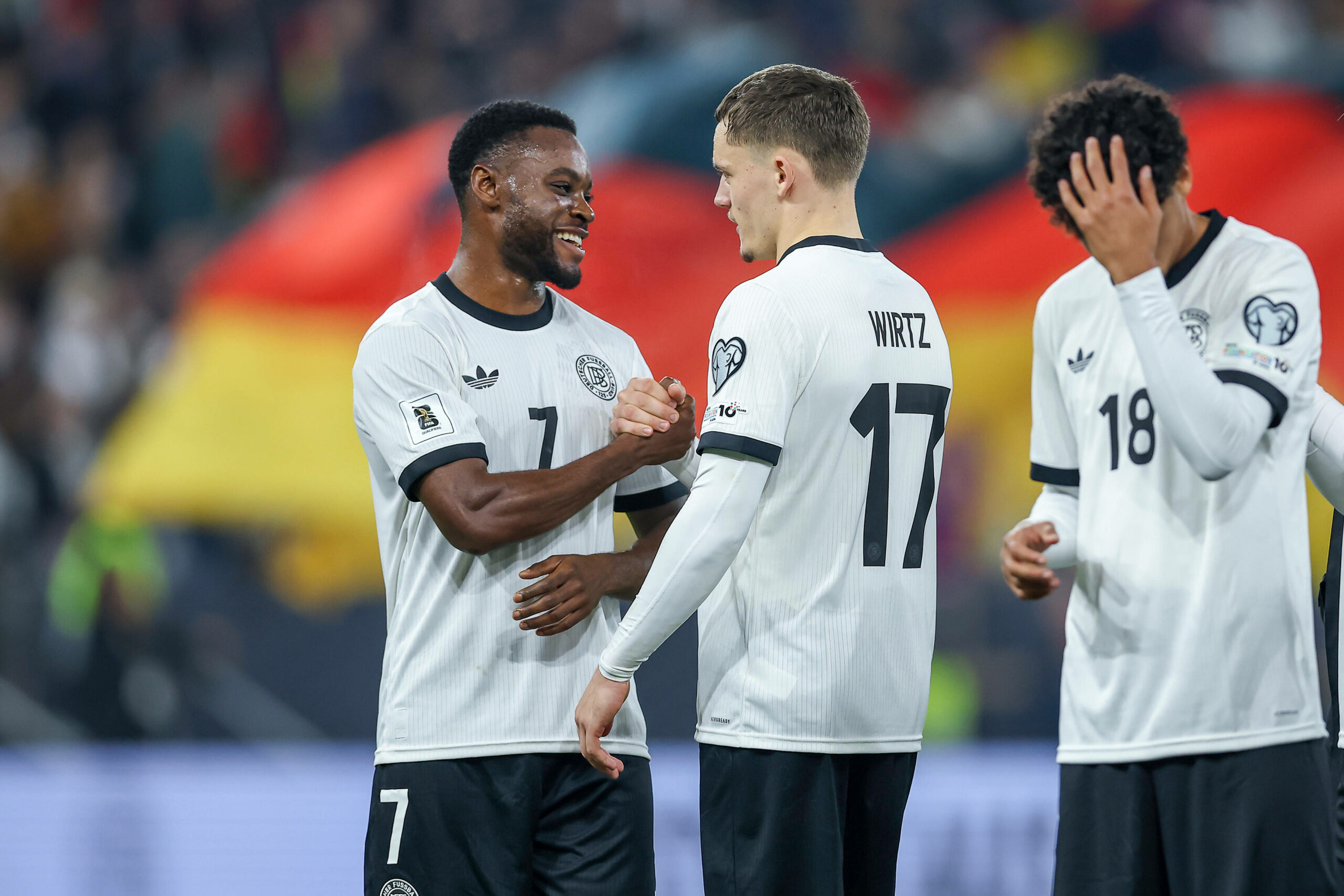 Ridle Baku und Florian Wirtz klatschen bei einem Länderspiel ab
