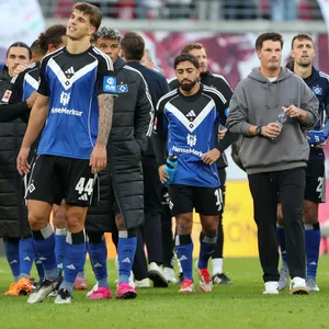 Merlin Polzin und die HSV-Profis gehen über das Spielfeld in Leipzig