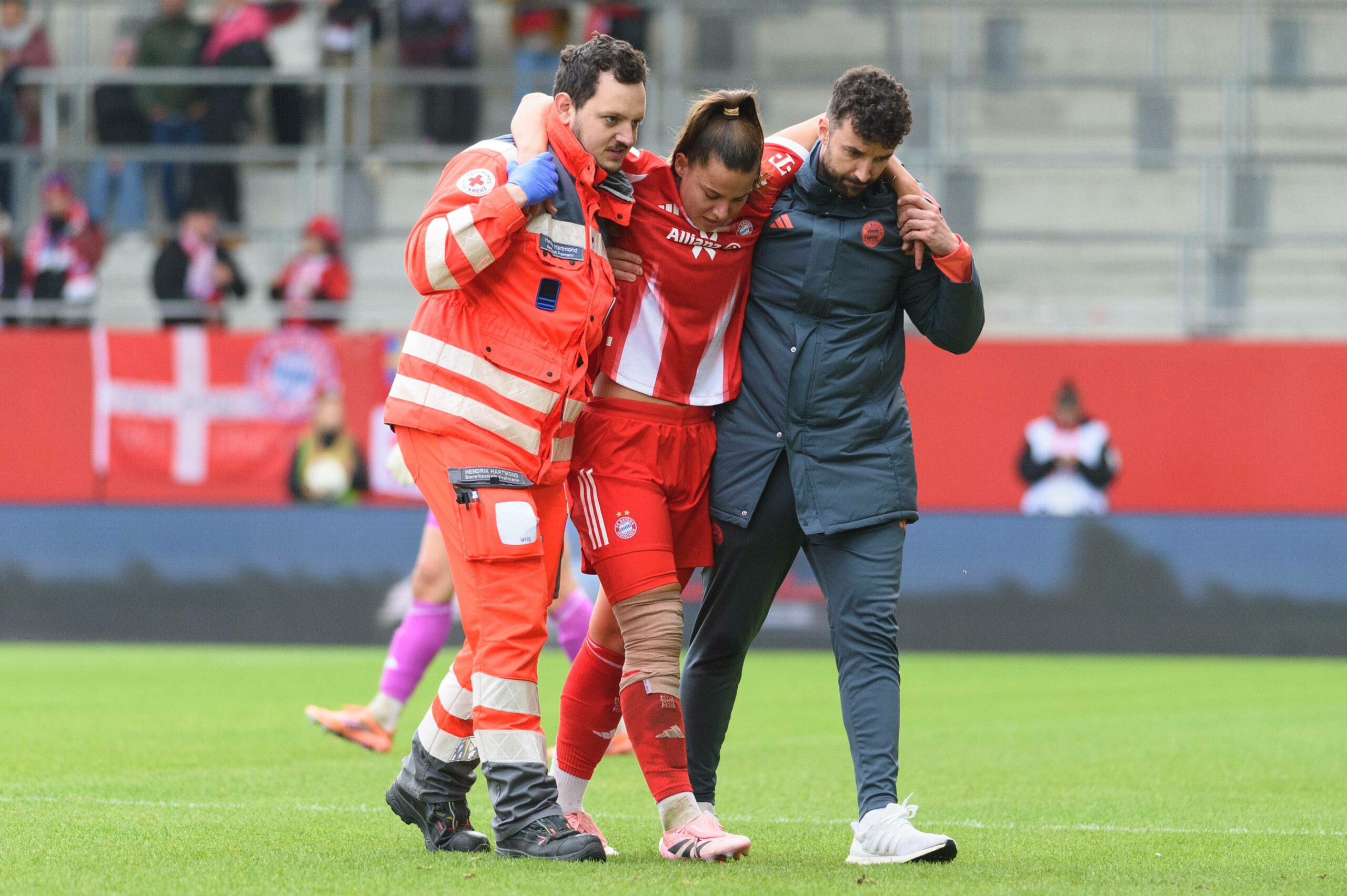 Lena Oberdorf wird von einem Sanitäter und einem Staff-Mitglied des FC Bayern gestützt und vom Feld gebracht