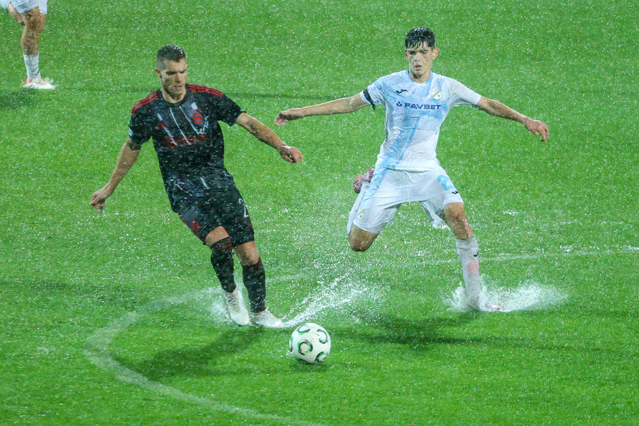 Martin Suchomel von Sparta Prag und Dominik Thaqi von HNK Rijeka im Kampf um den Ball auf dem unter Wasser stehenden Platz in Rijeka