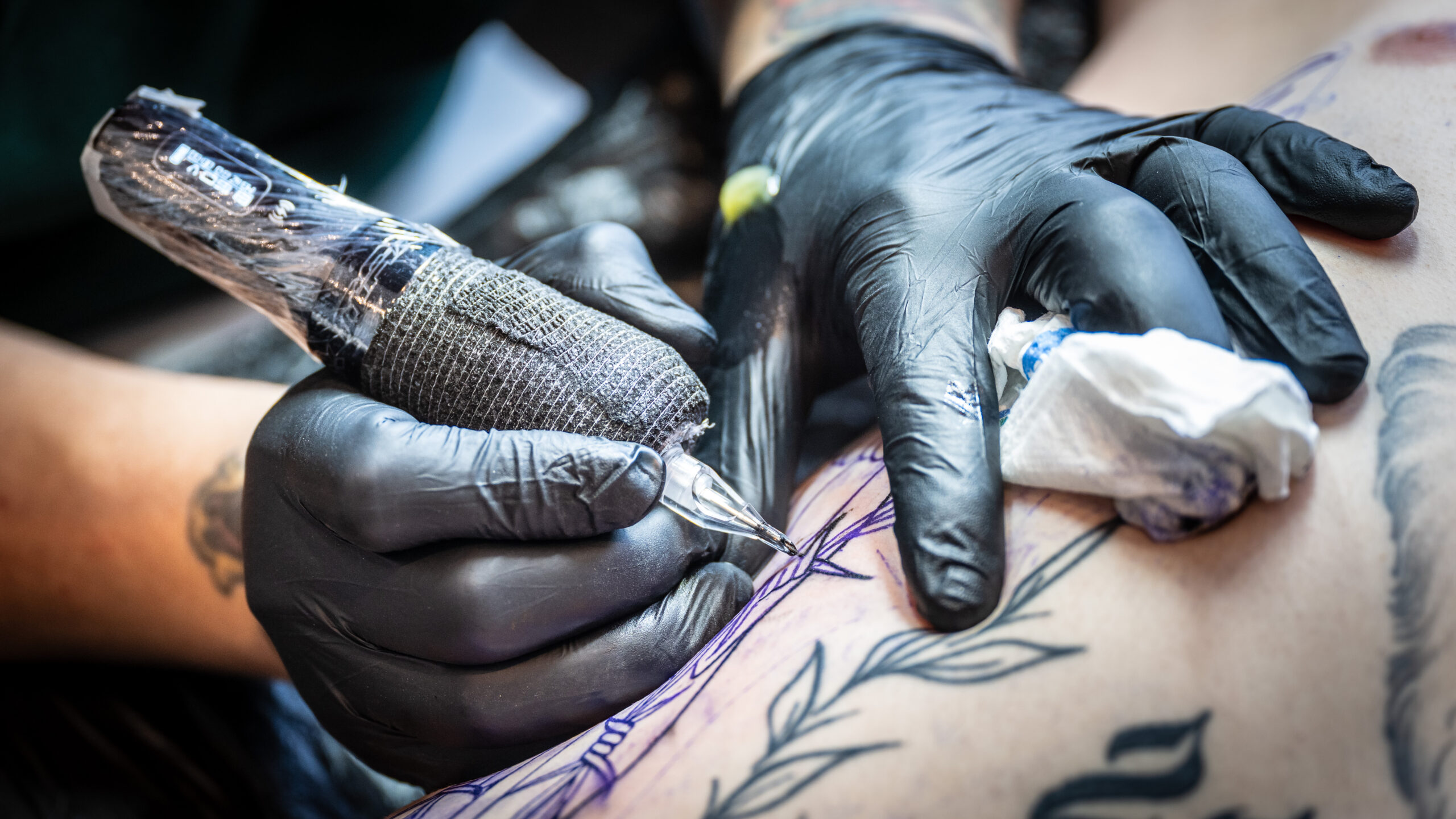 Ein Tattookünstler sticht ein Tattoo.