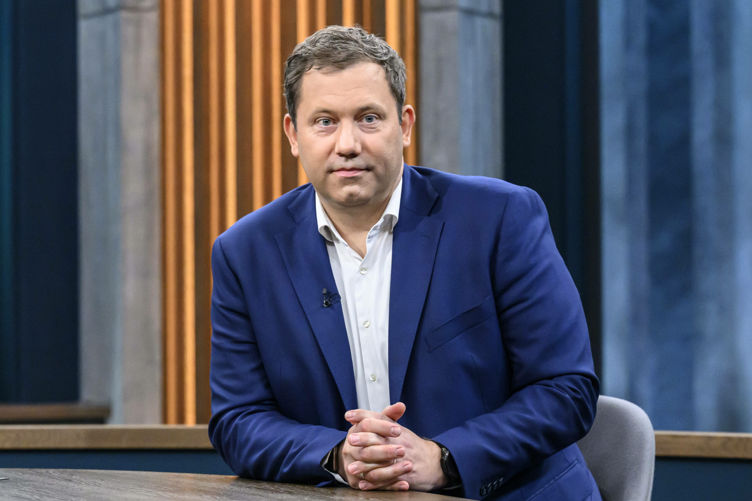 Lars Klingbeil sitzt mit verschränkten Händen an einem Tisch und schaut ernst in die Kamera.