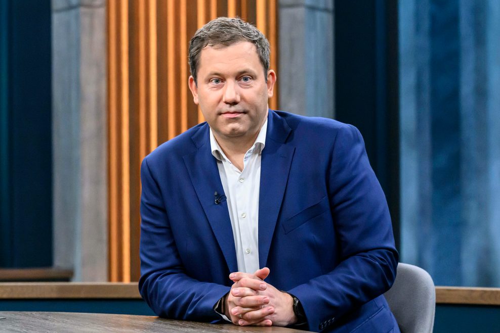Lars Klingbeil sitzt mit verschränkten Händen an einem Tisch und schaut ernst in die Kamera.