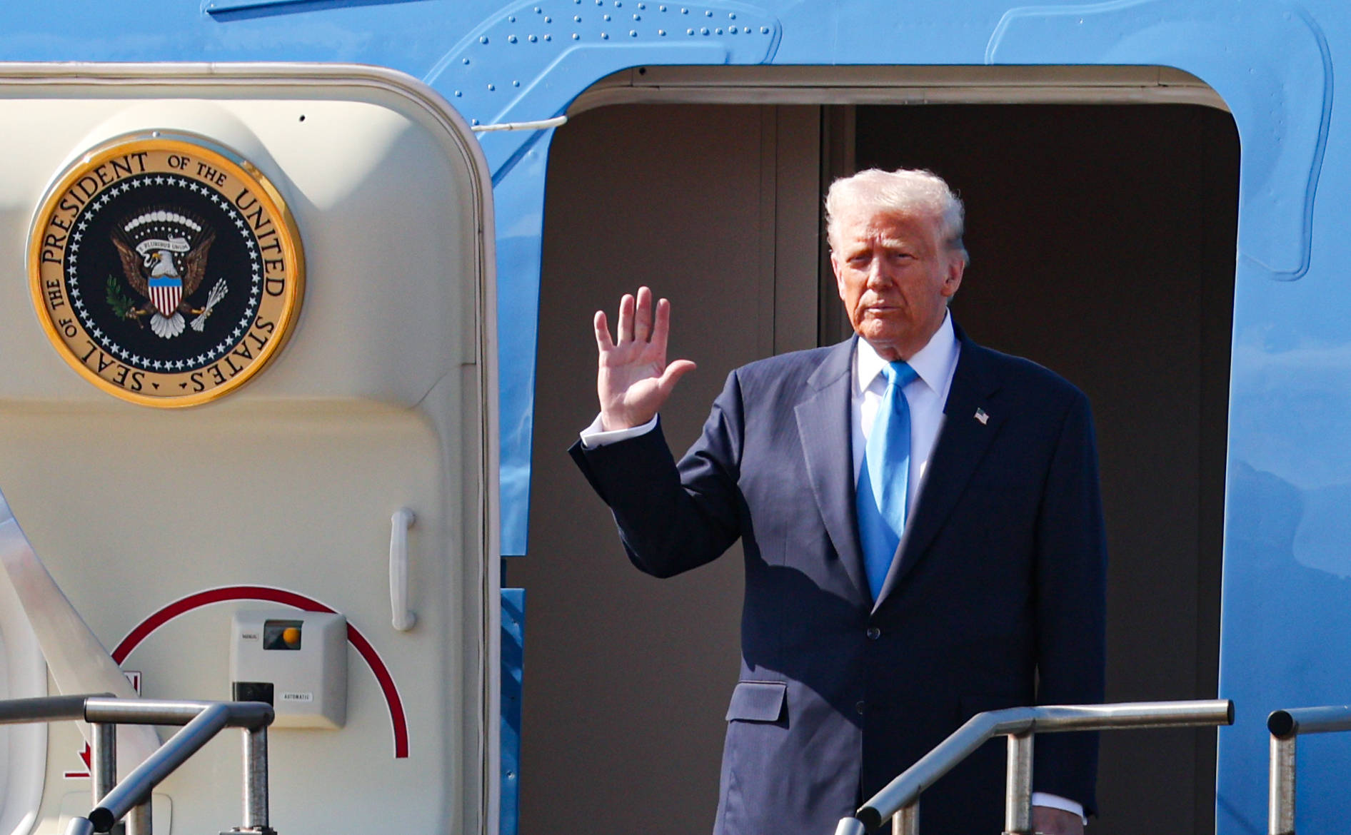 Trump steigt mit erhobener Hand aus der AirForce One.