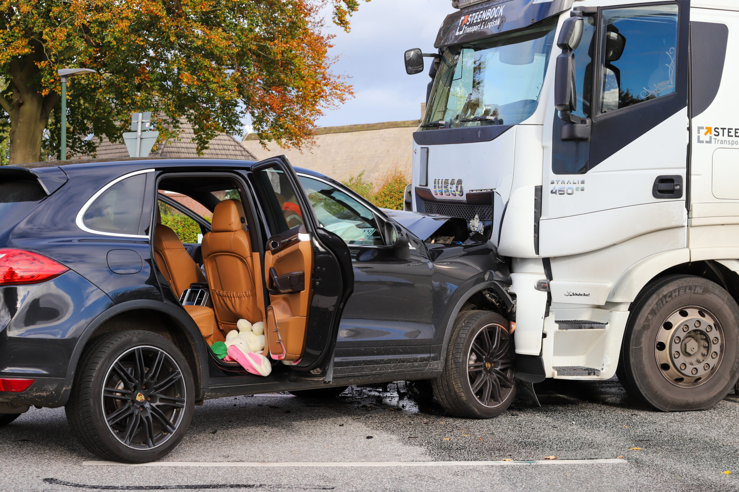 Ein schwarzer Porsche-SUV steht mit der Frontpartie in einen weißen Lastwagen gedrückt.