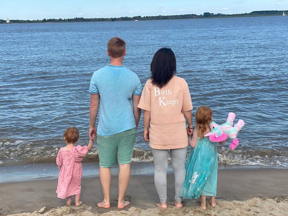 Die Familie steht mit dem Rücken zur Kamera am Meer.