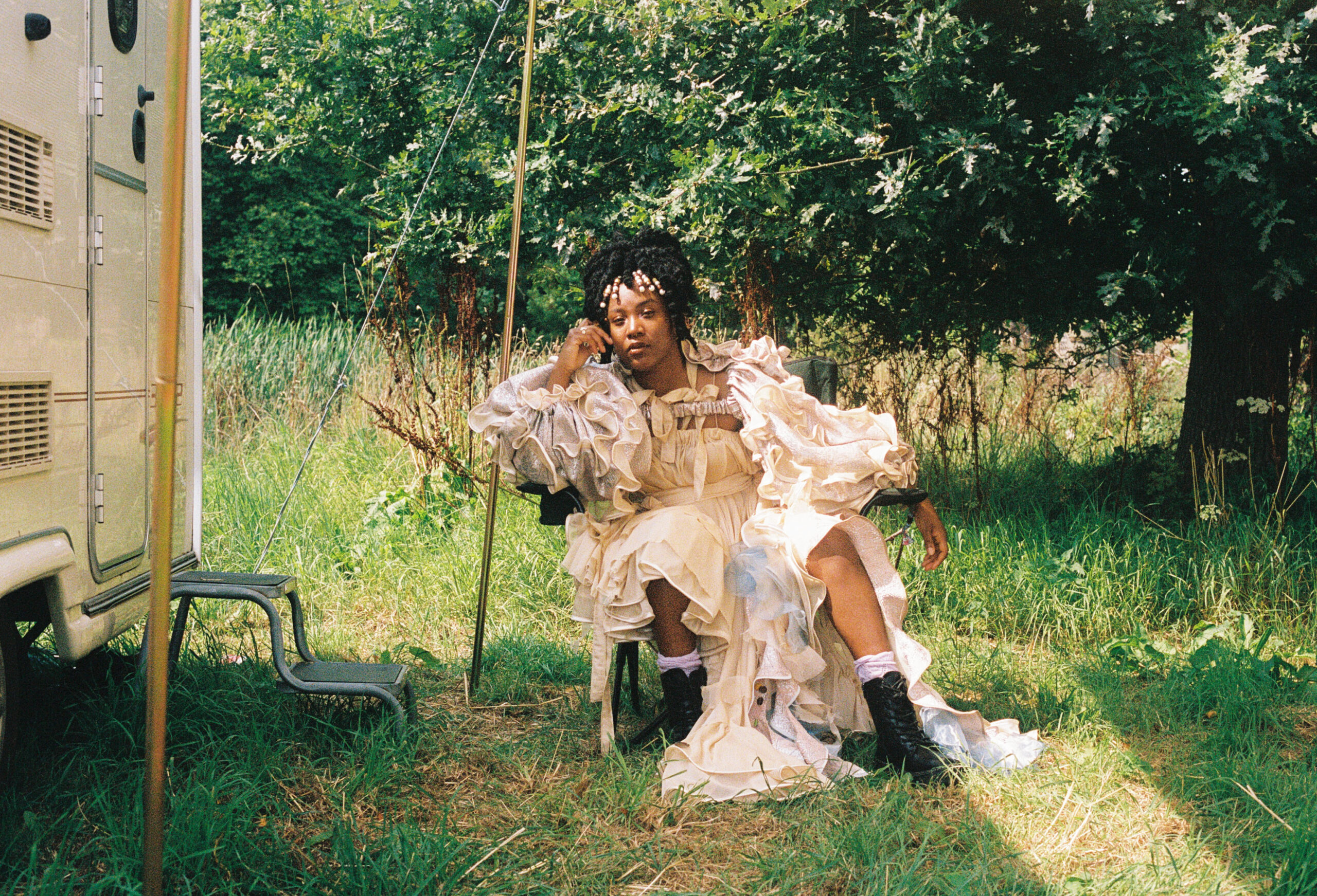 Sängerin Niecy Blues sitzt im Grünen vor einem Campingwagen.