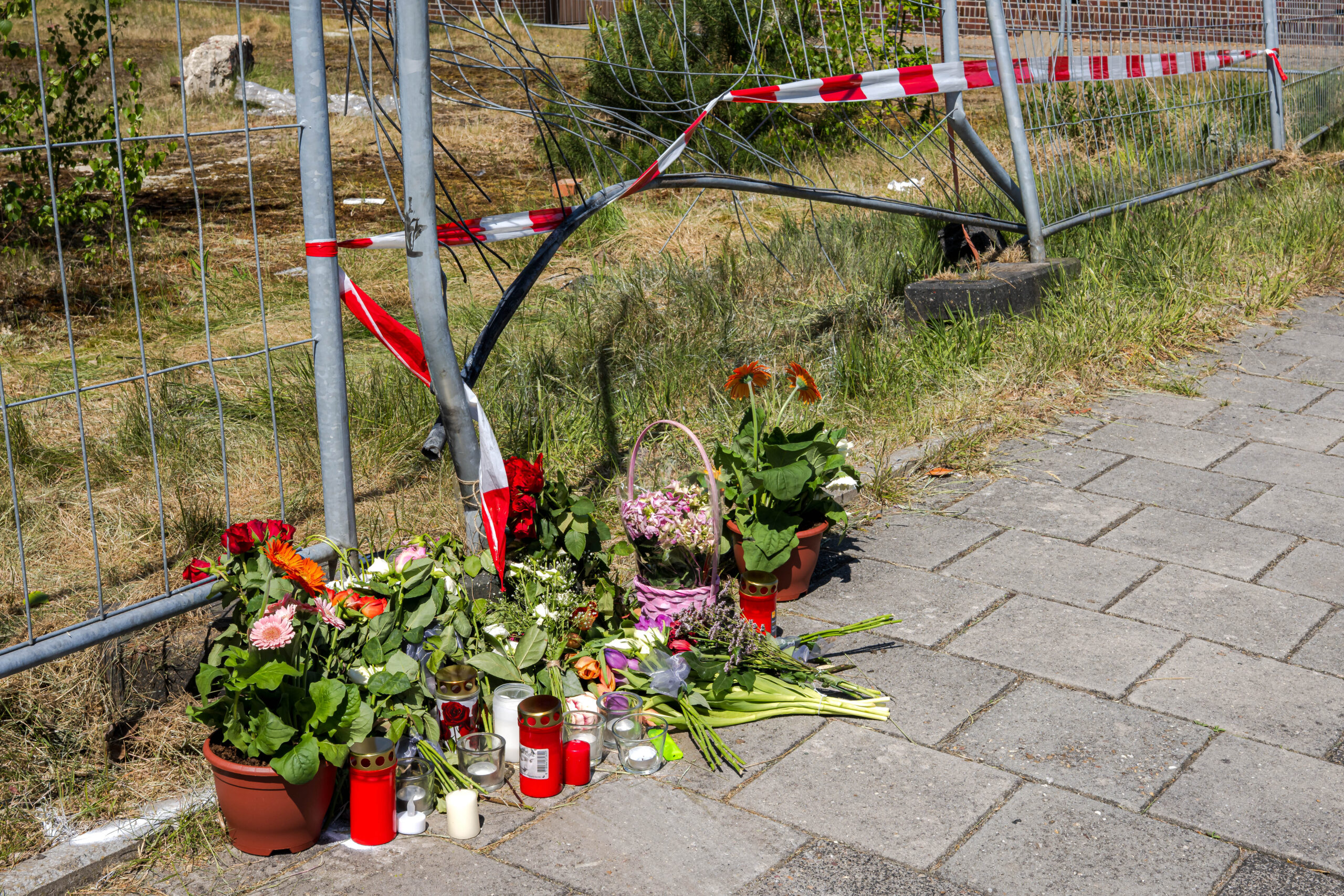 Blumen liegen am Tatort. Nach dem gewaltsamen Tod ermittelt die Polizei wegen Mordes.
