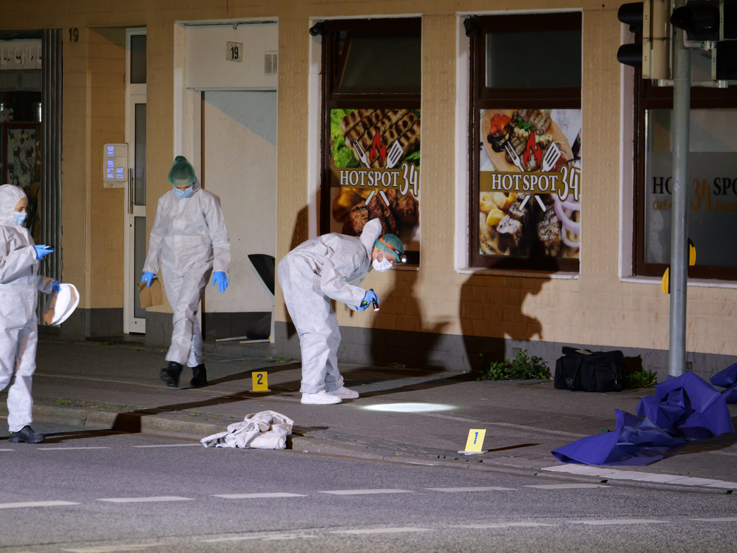 Polizisten in Schutzanzügen sichern Spuren am Tatort in Neumünster.