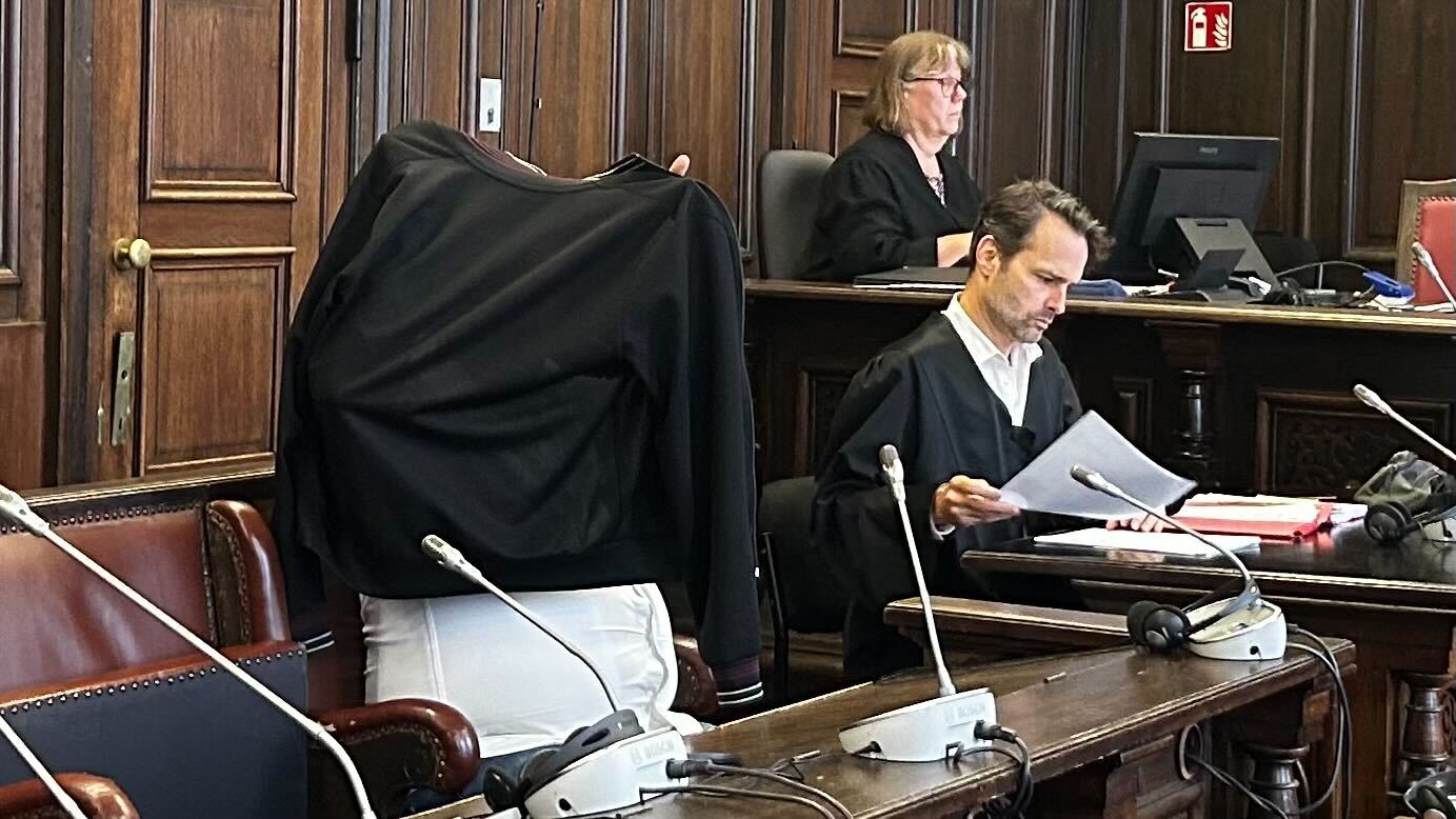 Der Angeklagte sitzt neben seinem Verteidiger im Gerichtssaal.