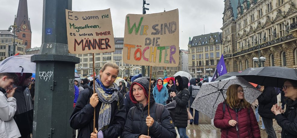 „Wir sind die Töchter“ und „Es waren nie MigrantInnen, es waren IMMER MÄNNER“ steht auf den Plakaten von Julie und Anne.