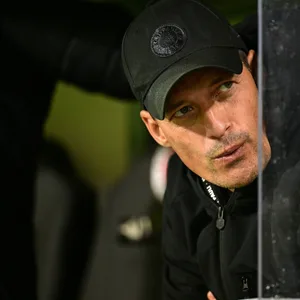 Alexander Blessin auf der Trainerbank zur Seite guckend und die Lippen spitzend