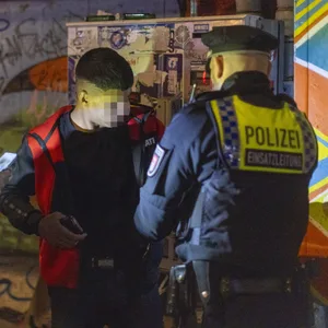 Drei Polizisten kontrollieren einen Jugendlichen