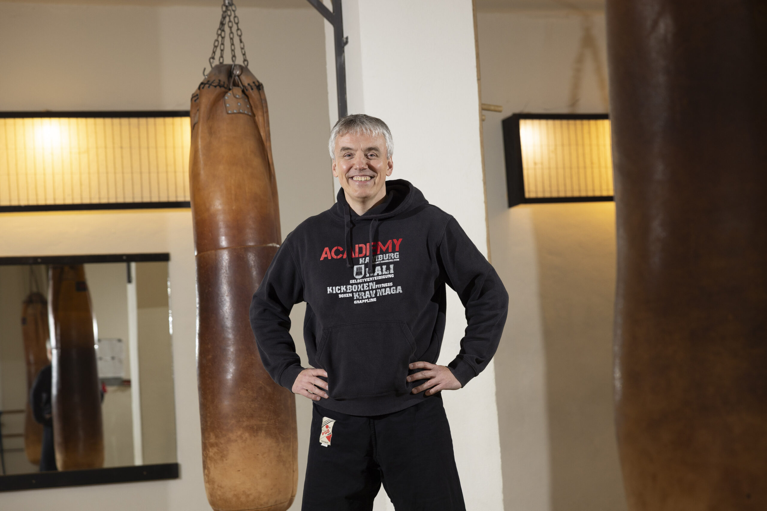 Marcus Ruddies steht zwischen zwei Trainingssäcken, die von der Decke hängen.