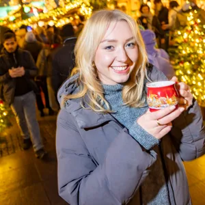 Frau auf dem Weihnachtsmarkt trinkt Glühwein