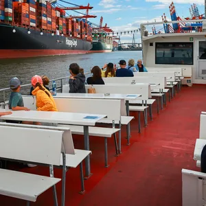Mit Blick auf große Containerschiffe fährt eine Barkasse von Barkassen-Meyer über die Elbe.
