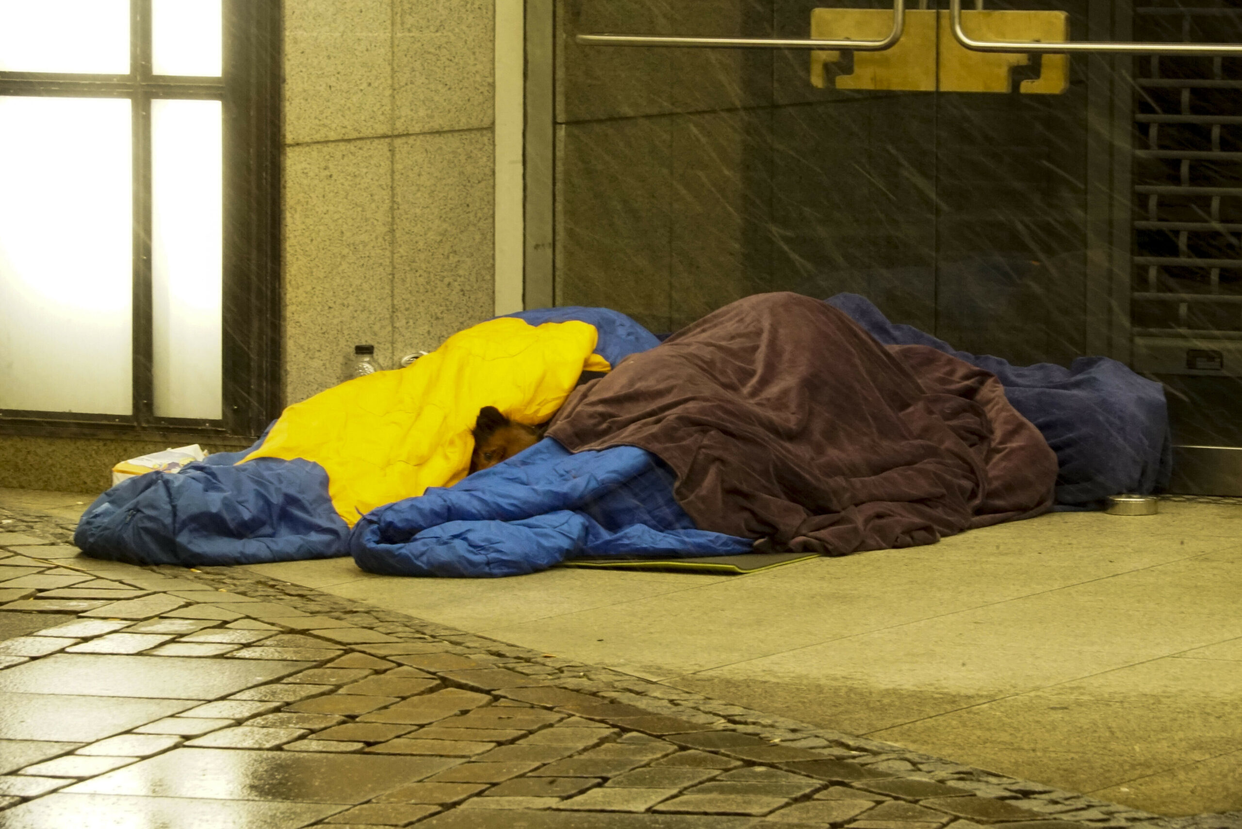 Menschen in Schlafsäcken am Boden