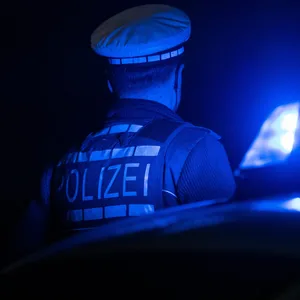Ein Polizist steht neben einem Polizeifahrzeug.