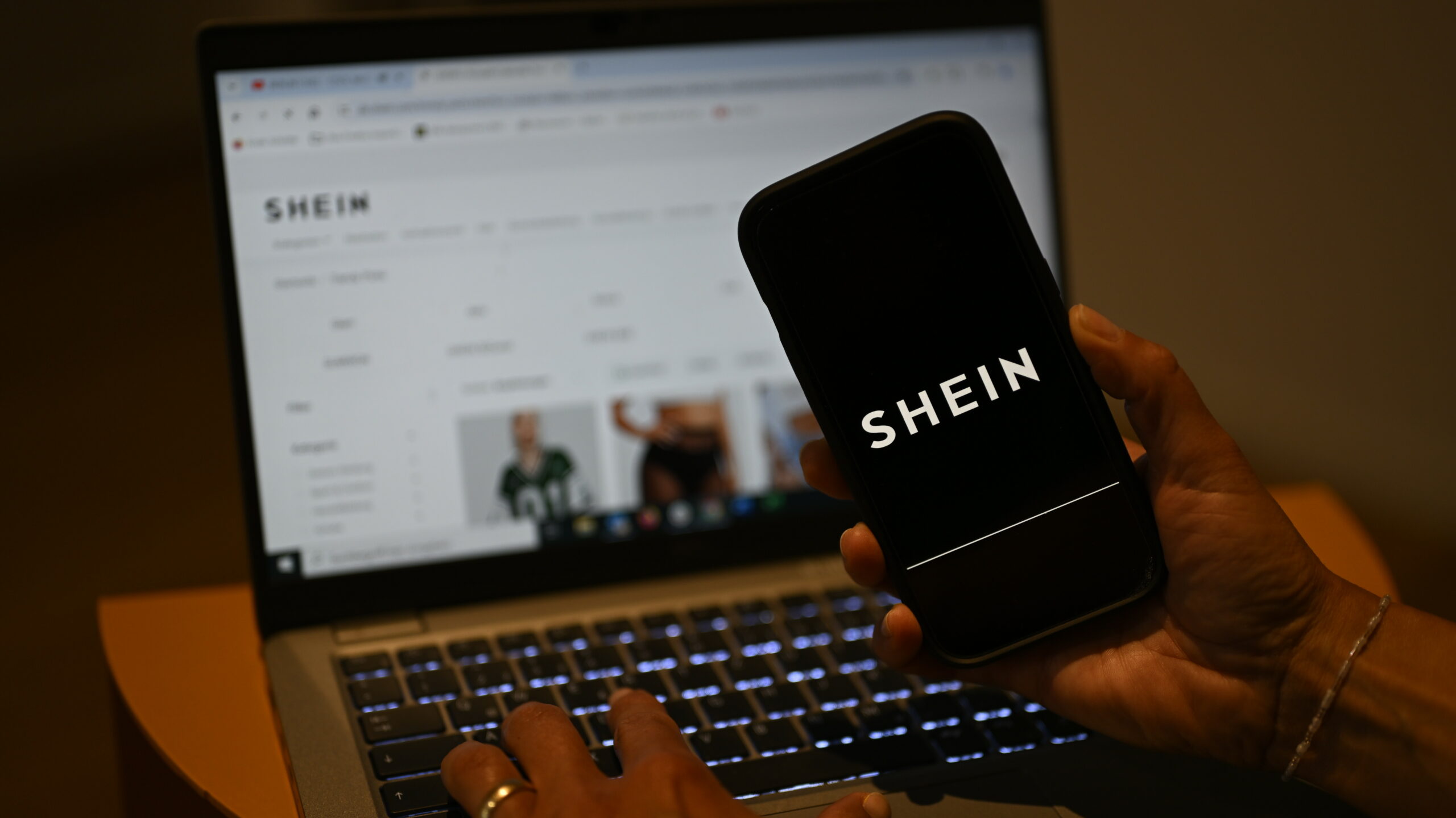 Das Shein-Logo ist auf einem Smartphone zu sehen, während die Webseite des chinesischen Online-Händlers auf einem Laptop geöffnet ist.