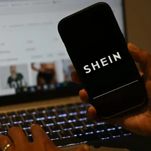 Das Shein-Logo ist auf einem Smartphone zu sehen, während die Webseite des chinesischen Online-Händlers auf einem Laptop geöffnet ist.