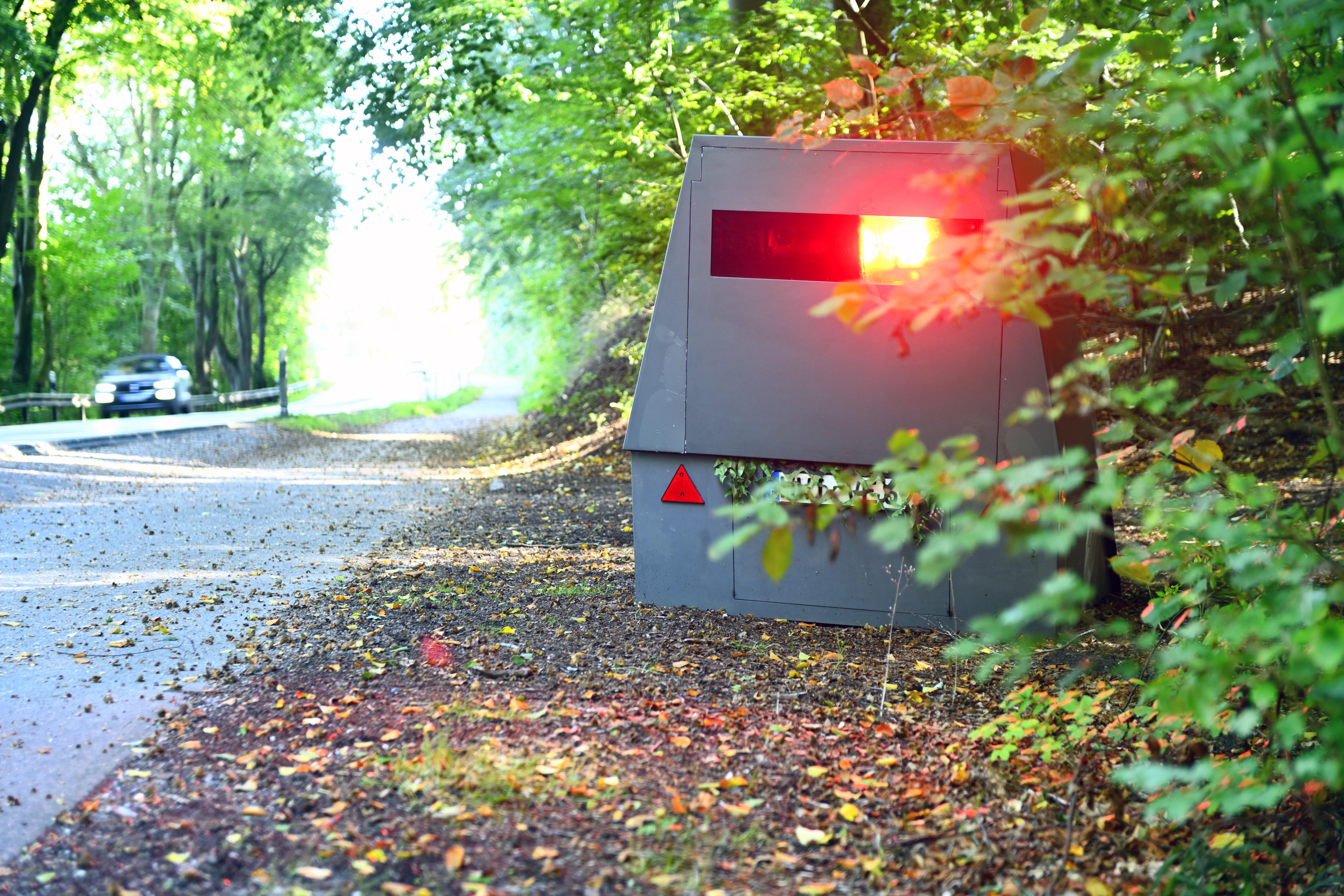 Eine Blitzeranhänger steht versteckt am Straßenrand (Symbolbild).