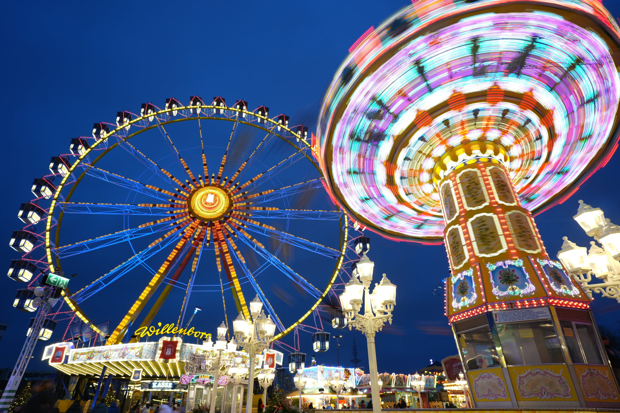 Hamburger Winterdom mit bunt beleuchtetem Riesenrad und Fahrgeschäft