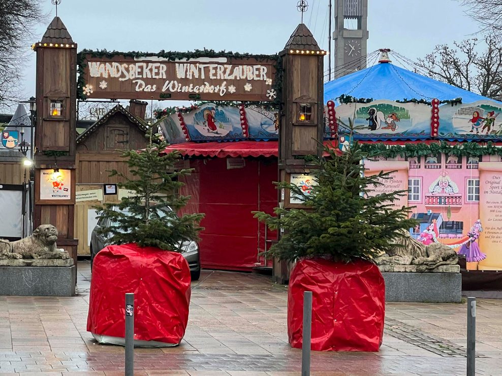 Mobile Straßensperren, mit Tannenbäumen dekoriert, sollen den Eingang vom Wandsbeker Winterzauber schützen.