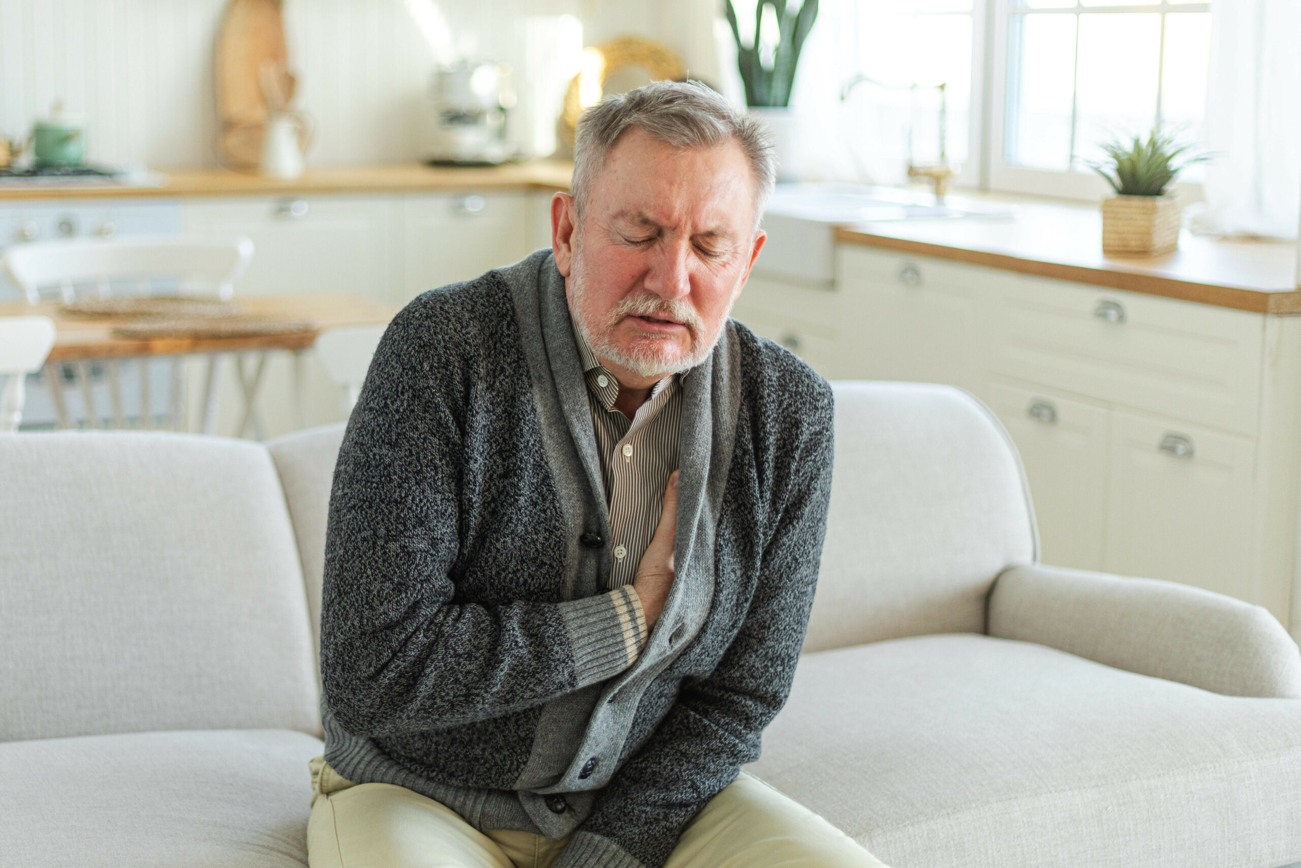 Ein älterer Mann hat Schmerzen am Herzen.