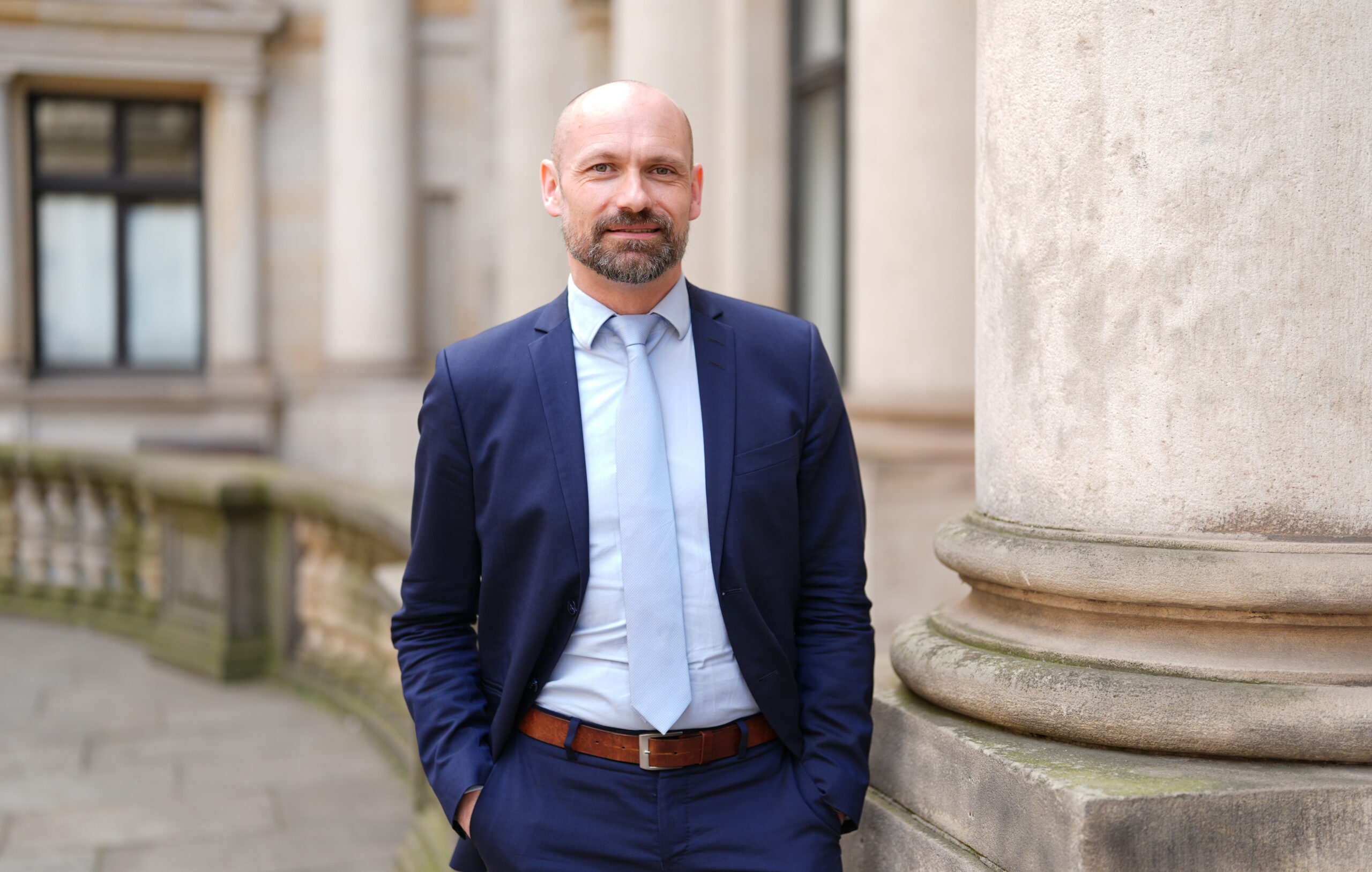 Mann in Anzug mit Krawatte vor Säulen