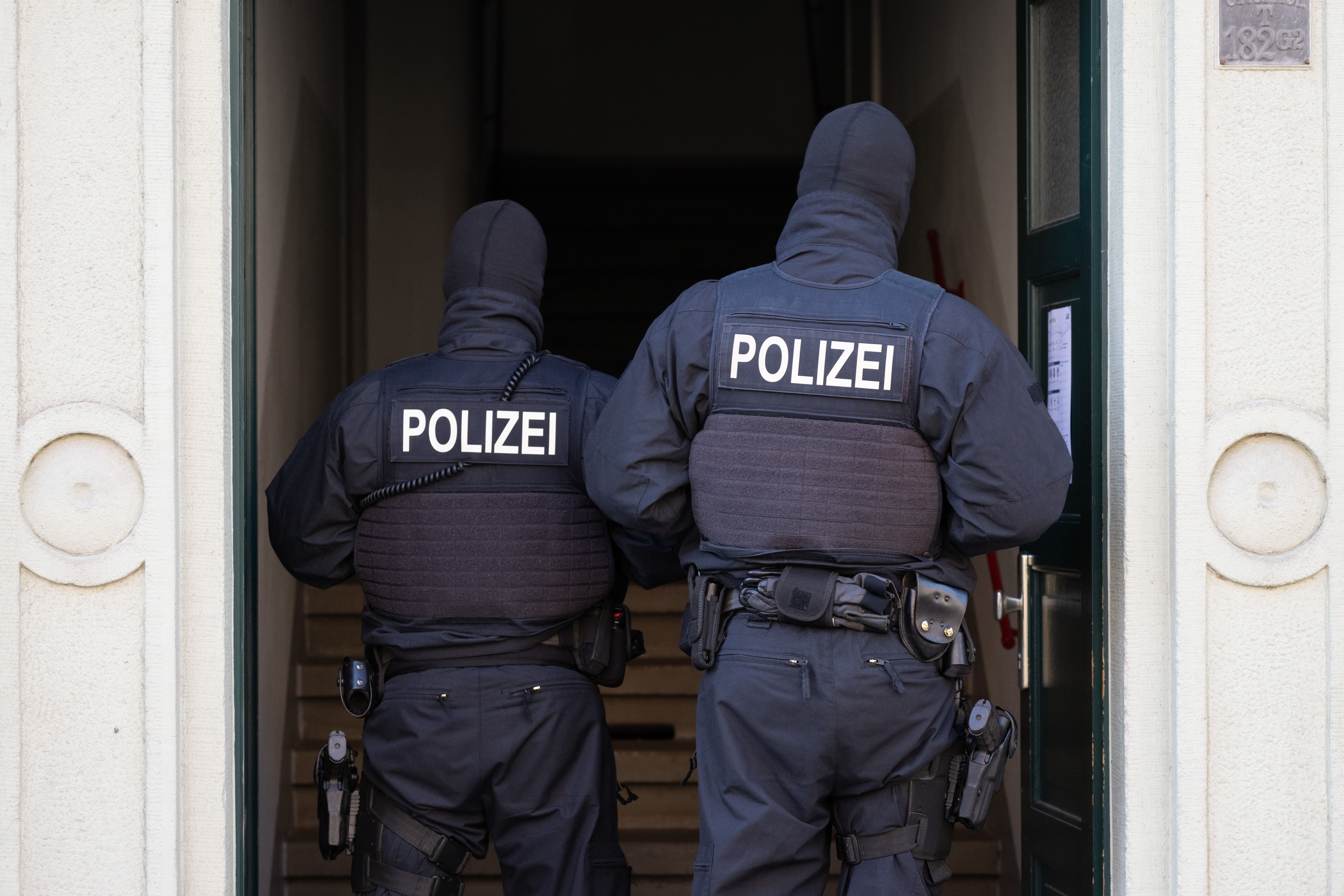 Polizisten stehen während einer Razzia in einem Hauseingang.