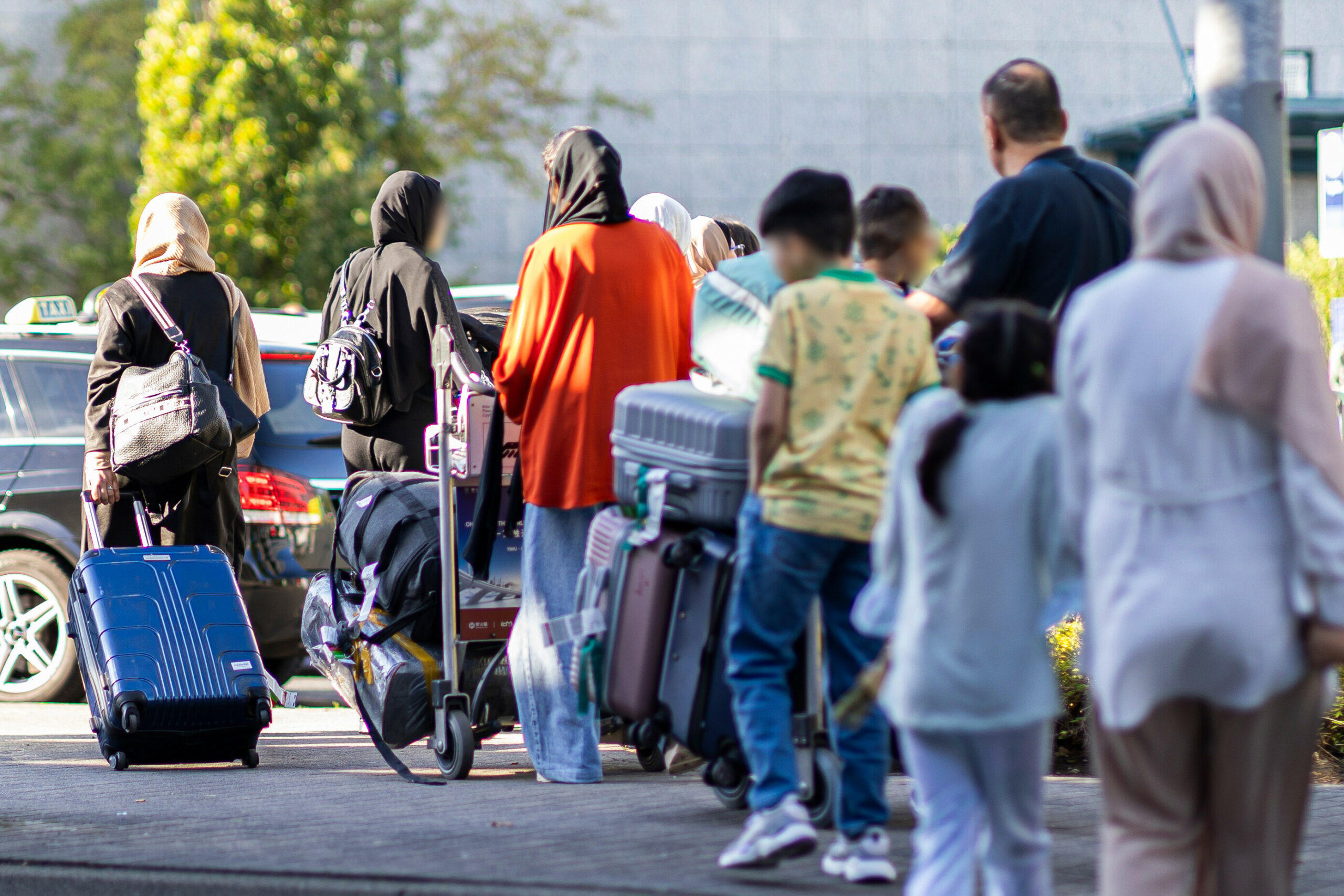 Menschen aus Afghanistan laufen mit ihrem Gepäck aus einem Flughafengebäude.