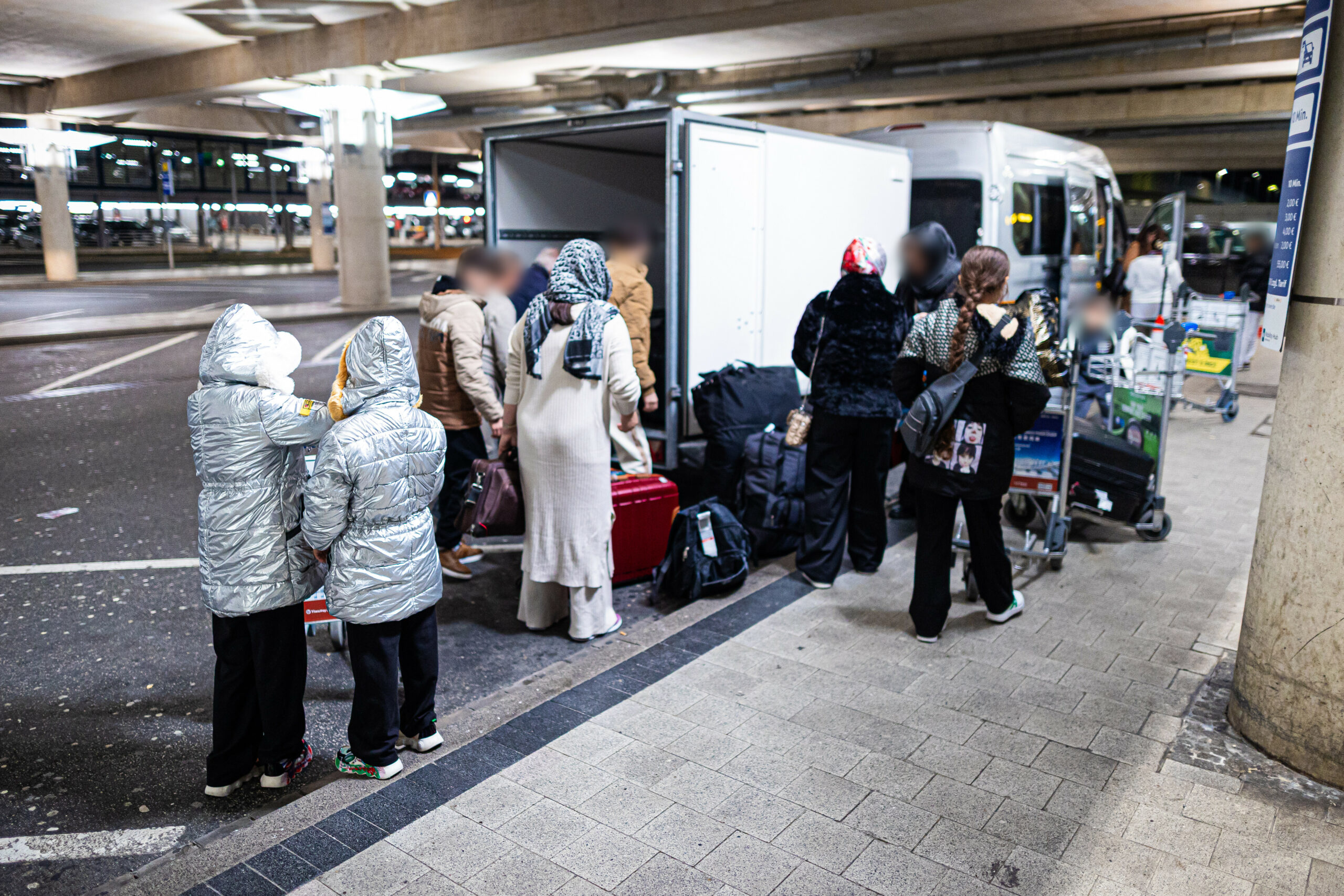 enschen aus Afghanistan, die zuvor mit einem Flugzeug auf dem Flughafen Hannover-Langenhagen gelandet sind, verstauen ihr Gepäck