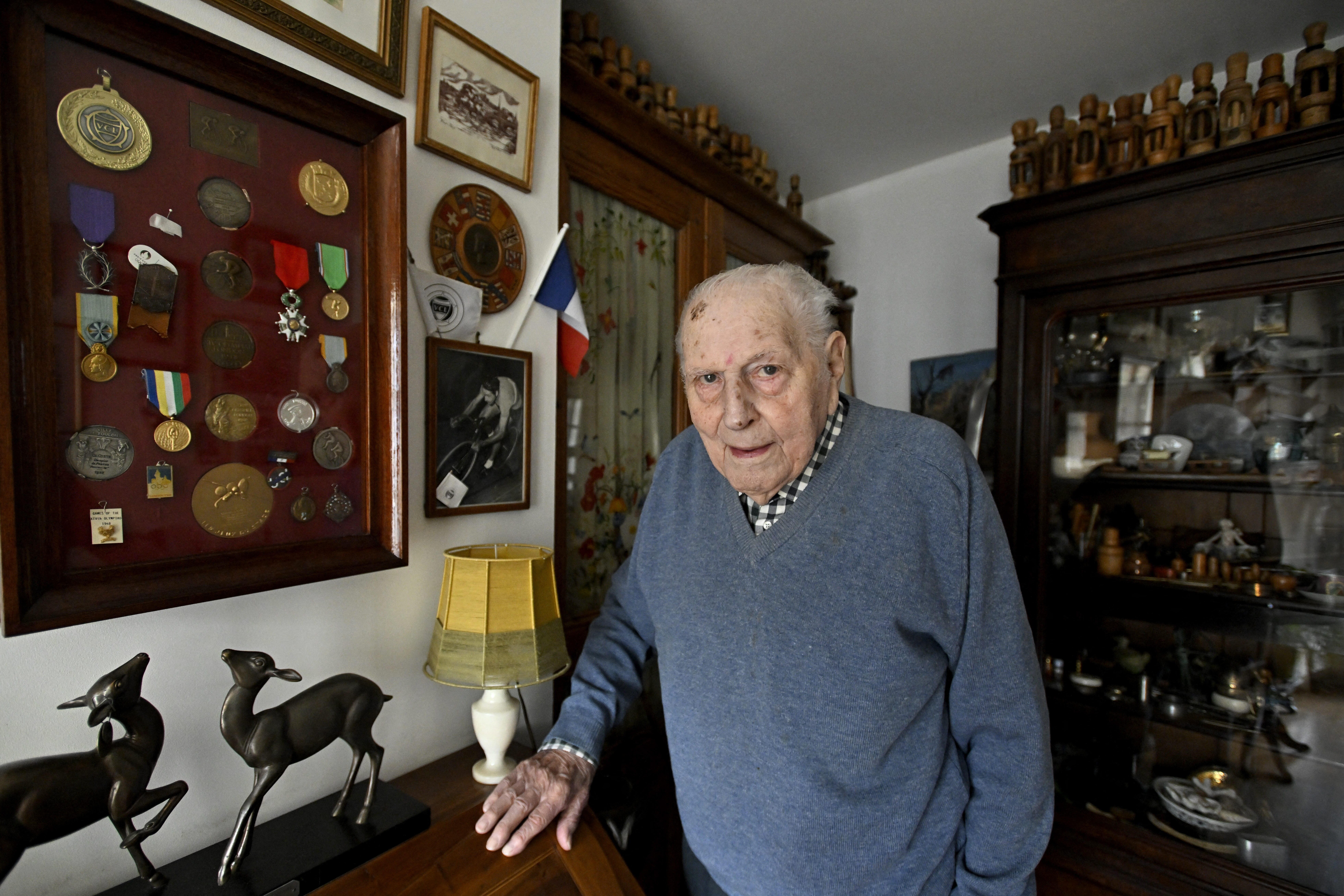 Charles Coste posiert vor seinen zahlreichen Auszeichnungen