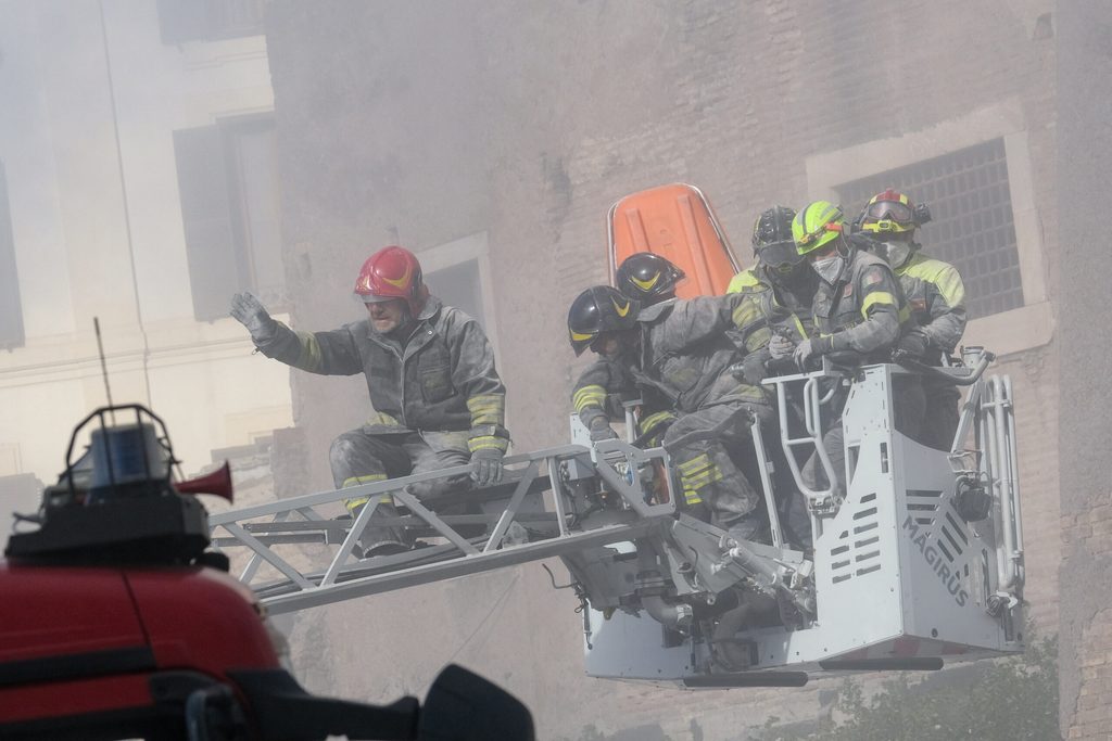 Einsatzkräfte der Feuerwehr gehen nach dem zweiten Einsturz eines Gebäudeteils, an dem Restaurierungsarbeiten durchgeführt wurden, in Deckung.