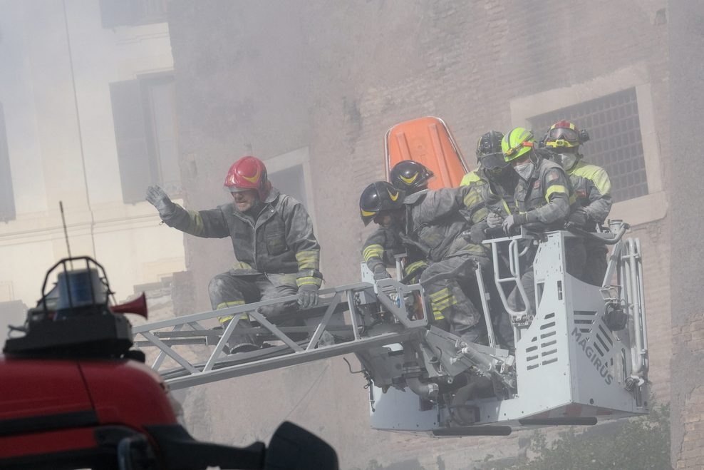 Einsatzkräfte der Feuerwehr gehen nach dem zweiten Einsturz eines Gebäudeteils, an dem Restaurierungsarbeiten durchgeführt wurden, in Deckung.