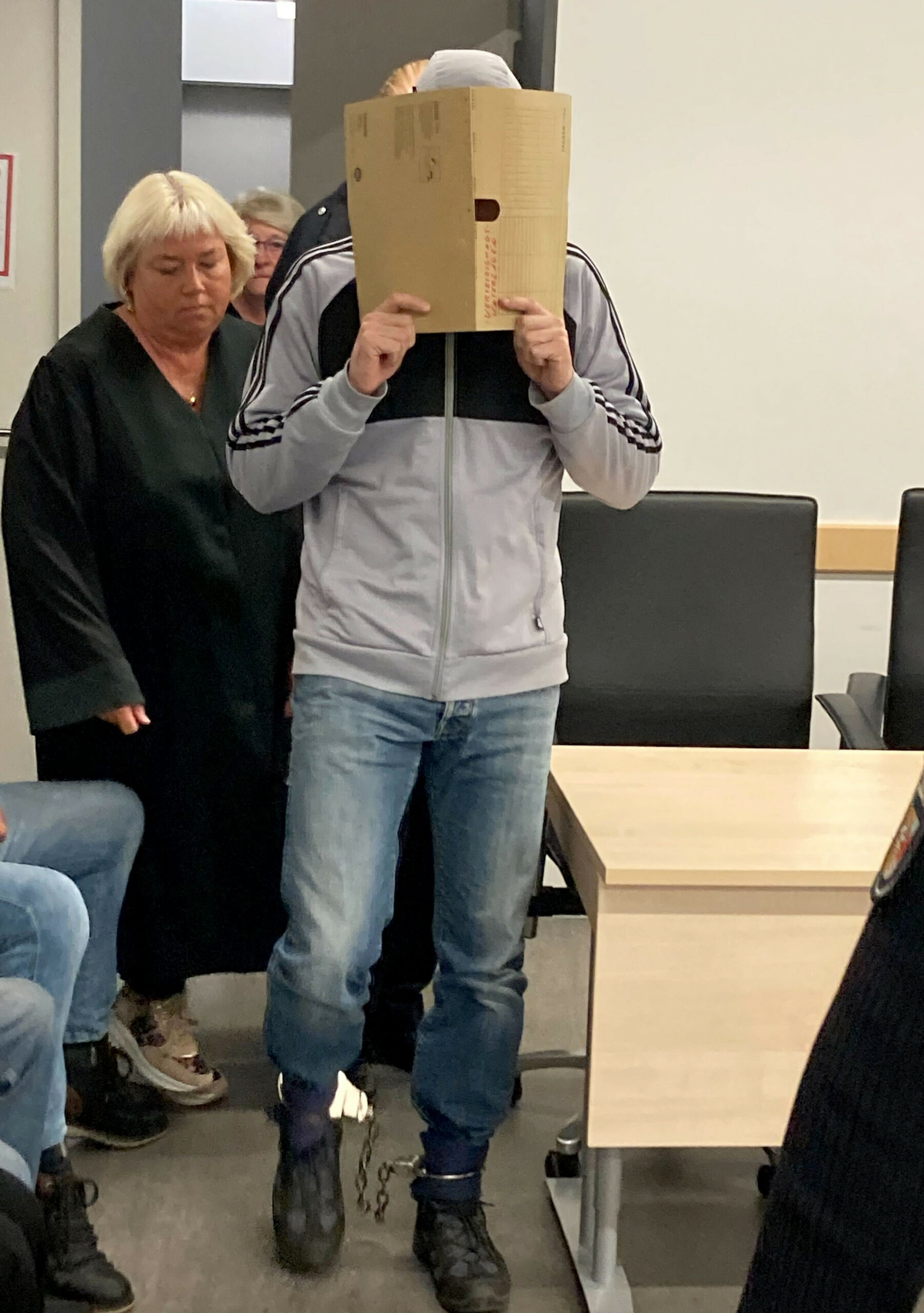 Der Angeklagte kommt mit Fußfesseln neben seiner Verteidigerin in den Gerichtssaal im Landgericht zum Prozess wegen sexuellen Missbrauchs