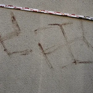 Kriminalexperten messen Hakenkreuze an einem Haus in Hanau.