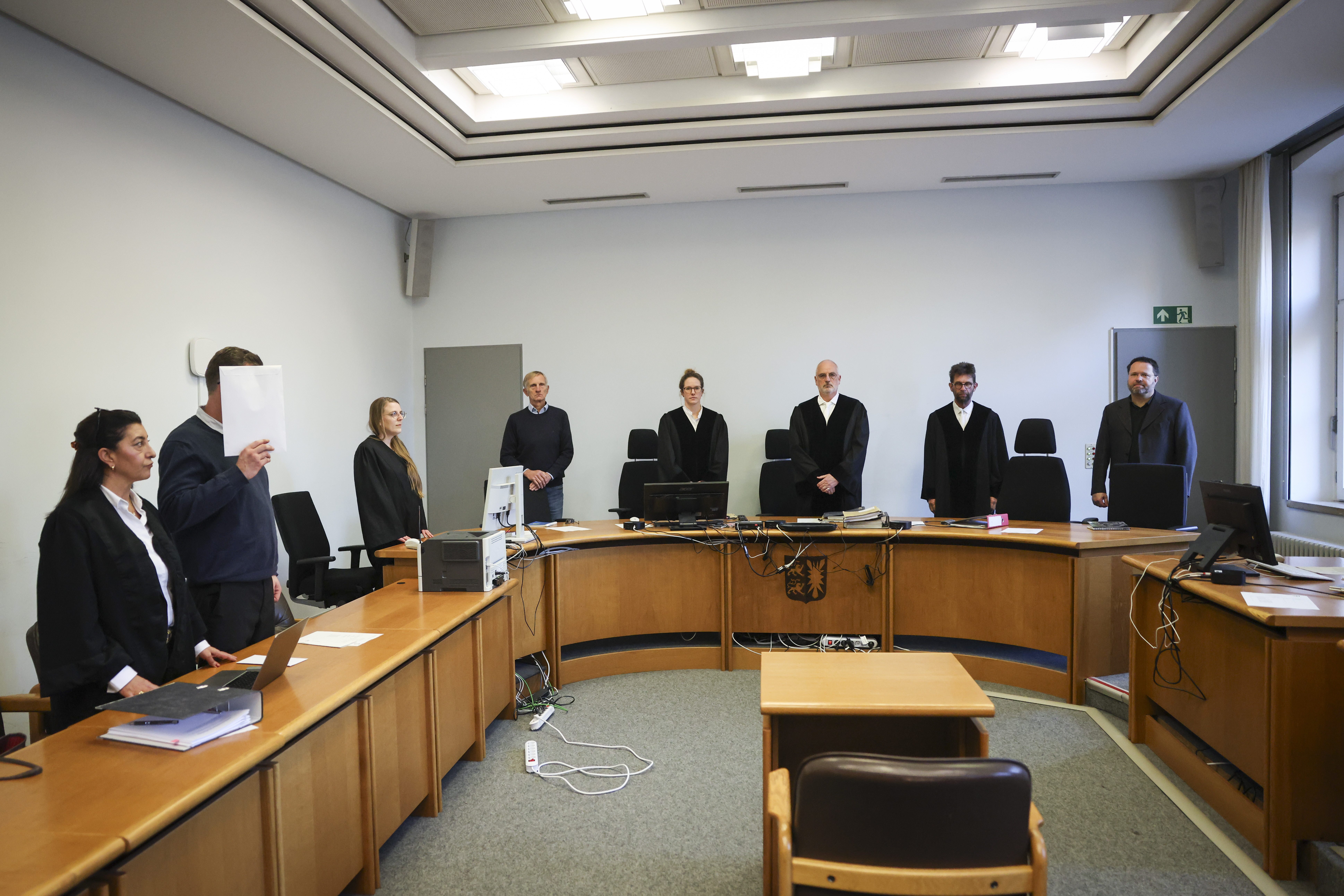 Stefan Becker (3.v.r), Vorsitzender Richter, der Angeklagte (2.v.l), seine Anwältin Gülbahar Kisin (l) und weitere Prozessbeteiligte stehen im Gerichtssaal zu Beginn eines Prozesses vor dem Landgericht. Am Donnerstag begann der Prozess gegen den 39-Jährigen wegen Totschlags.