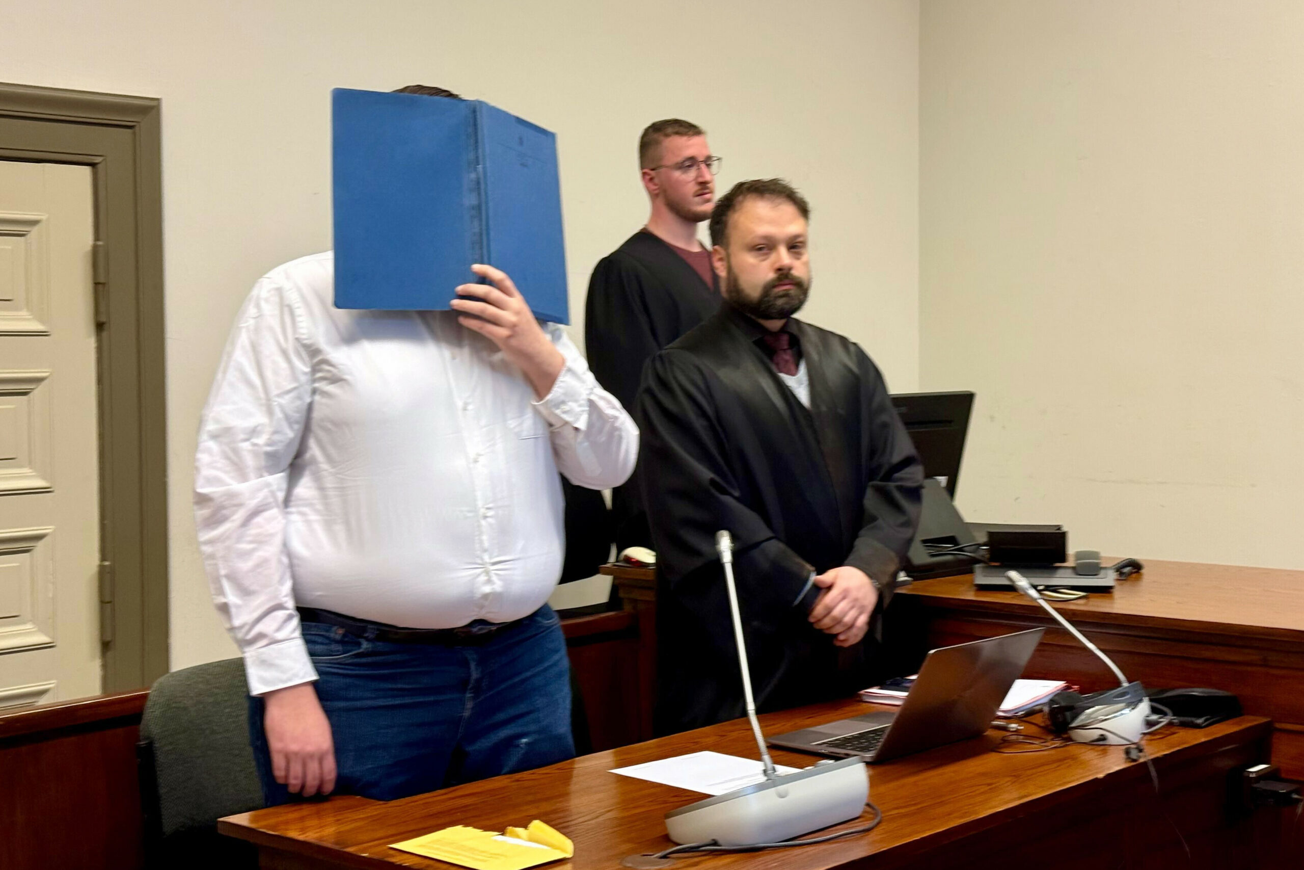 Der 26-jährige Angeklagte steht im Gerichtssaal neben seinem Verteidiger.