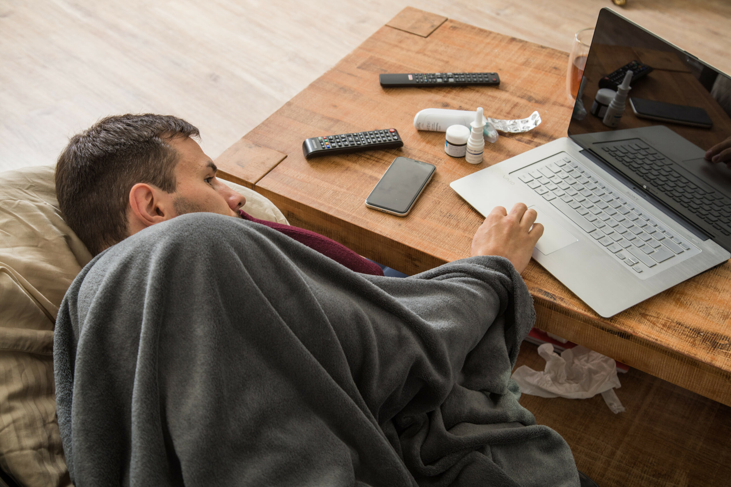 Ein Mann mit Erkältung bedient ein Laptop.