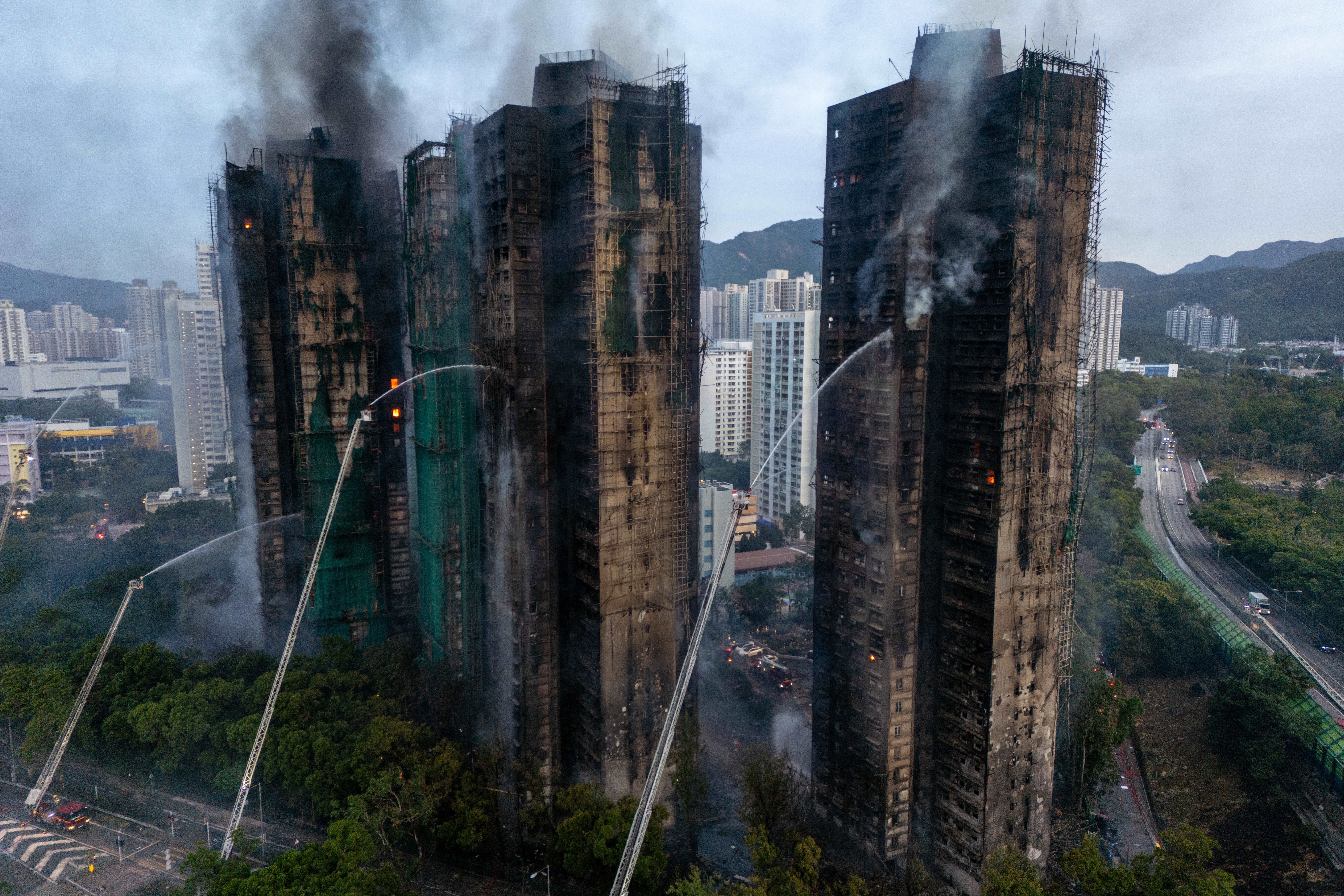 Auch am Morgen nach dem Großbrand in Hongkong ist die Feuerwehr weiter im Dauereinsatz.
