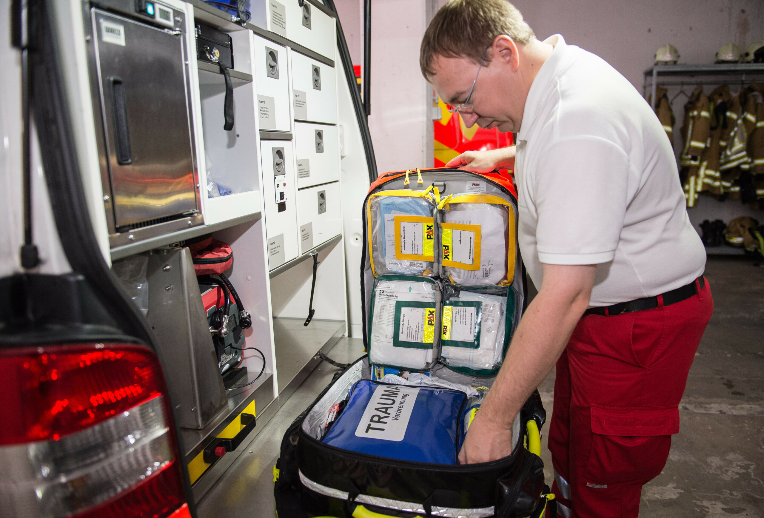 Mitarbeiter des Rettungsdienstes öffnet den Notfallrucksack im Rettungswagen